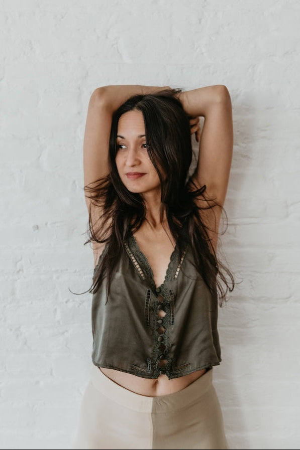 Woman wearing a green embroidery top against a white wall