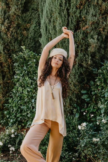 Woman in a beige outfit standing in a garden with greenery
