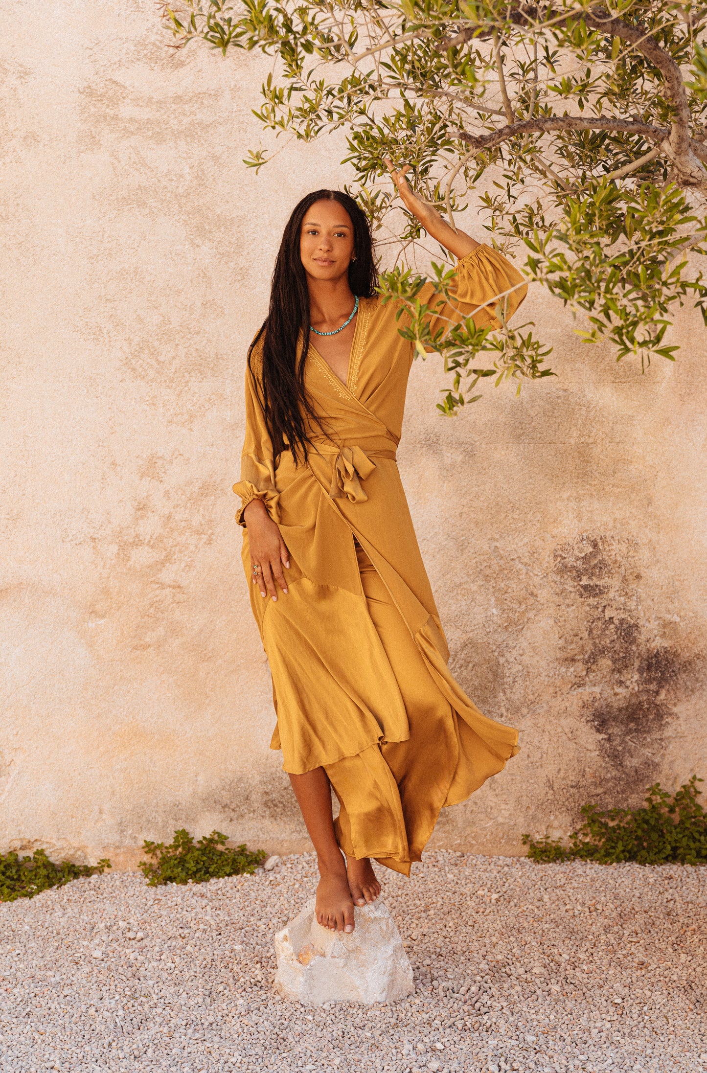 women wearing a Golden silk wrap dress with flowing balloon sleeves
