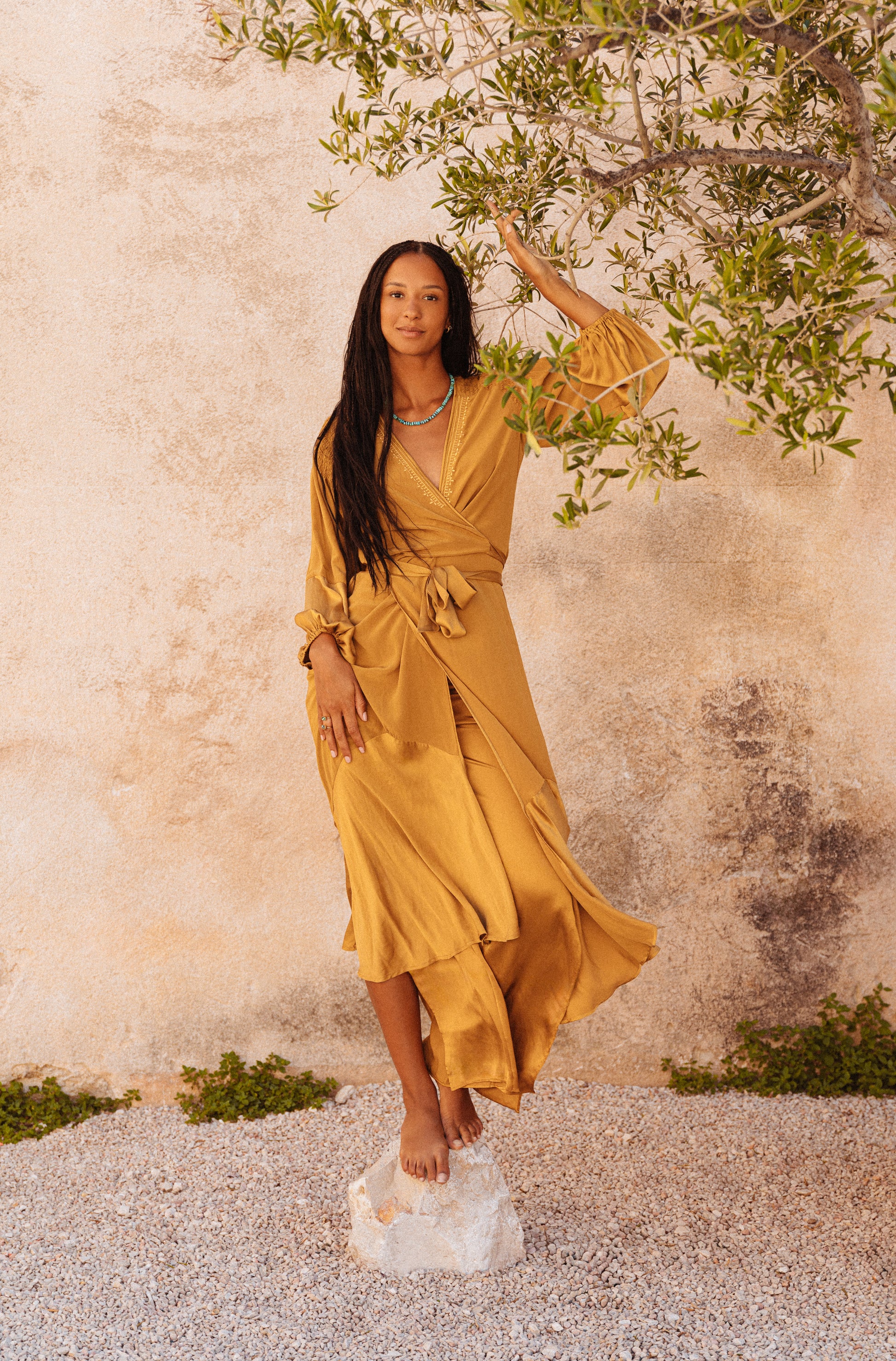women wearing a Golden silk wrap dress with flowing balloon sleeves
