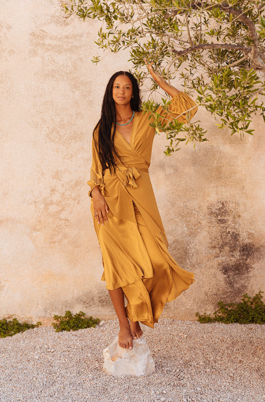 women wearing a Golden silk wrap dress with flowing balloon sleeves
