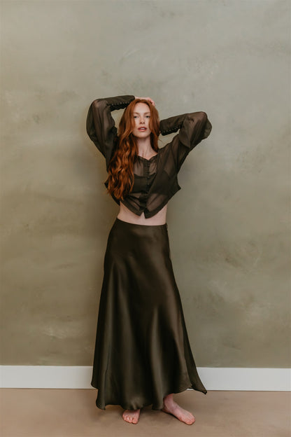 Woman in a dark green outfit posing against a plain background
