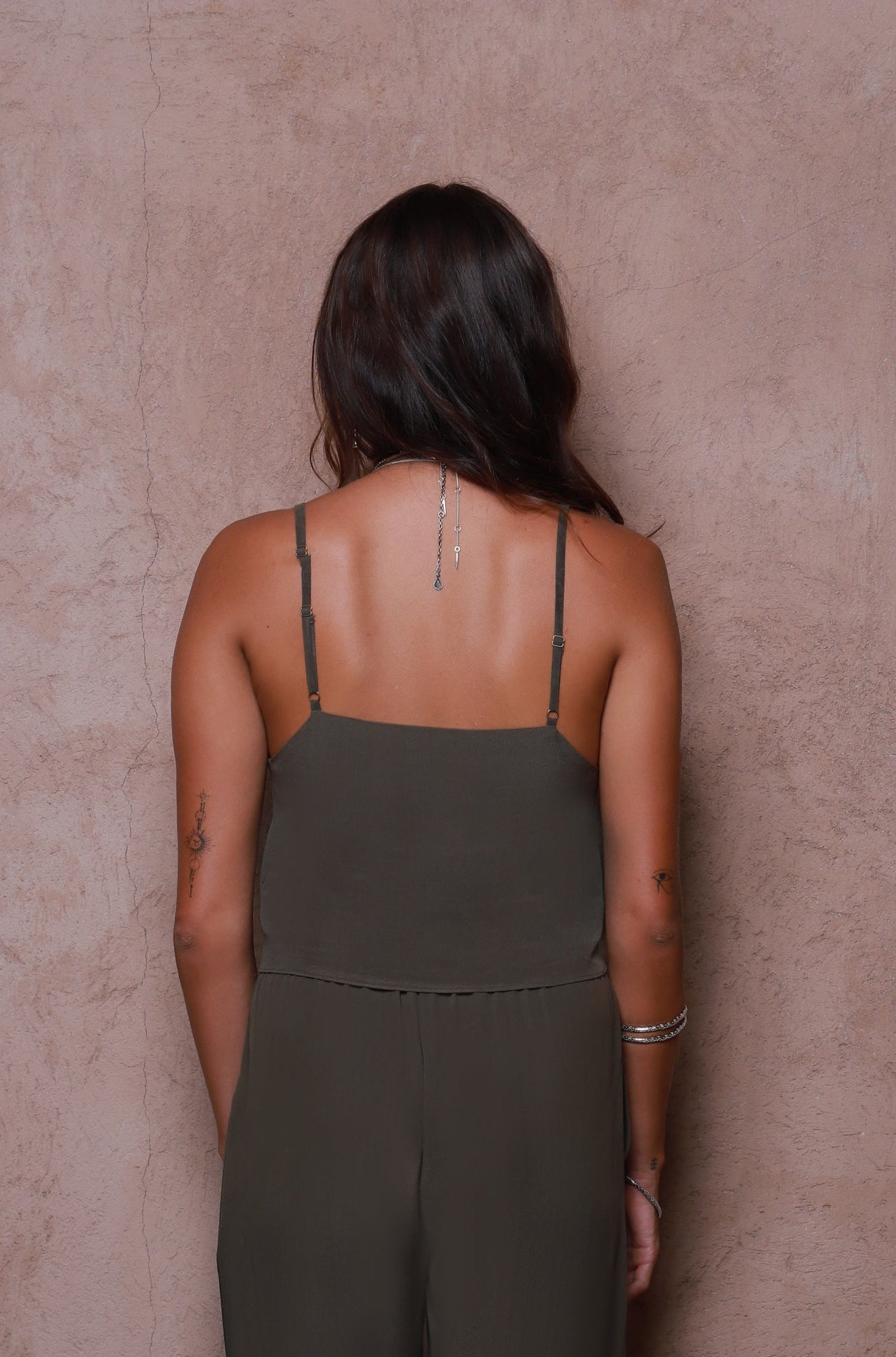Woman wearing a green jumpsuit against a beige wall
