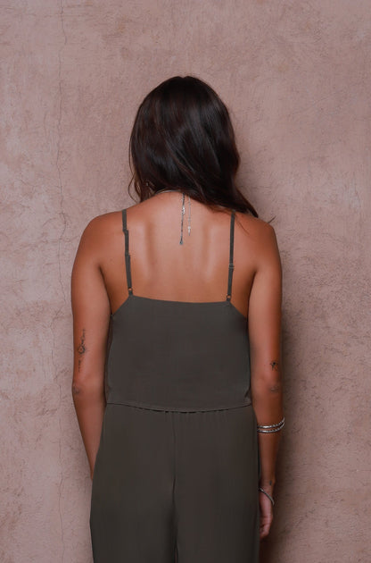 Woman wearing a green jumpsuit against a beige wall