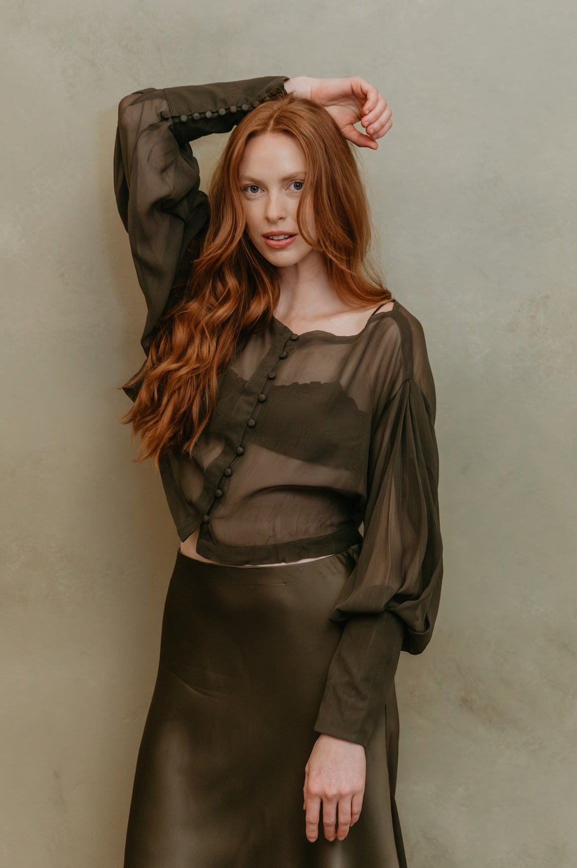 Woman wearing a dark green outfit against a plain background