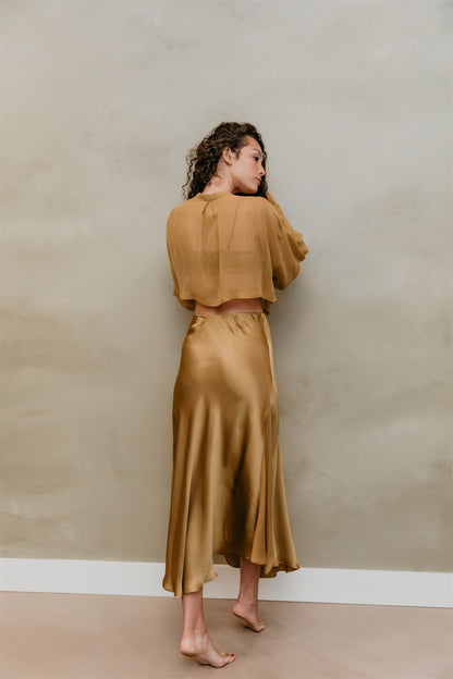 Woman wearing a brass outfit against a plain wall