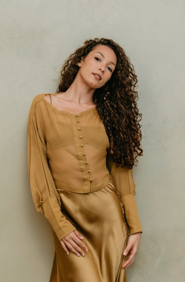 Woman wearing a chiffon silk  blouse against a plain background