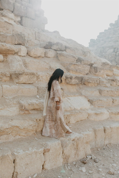 Model walking in a flowing linen kaftan dress by Payet Maison with deep V neckline and balloon sleeves.