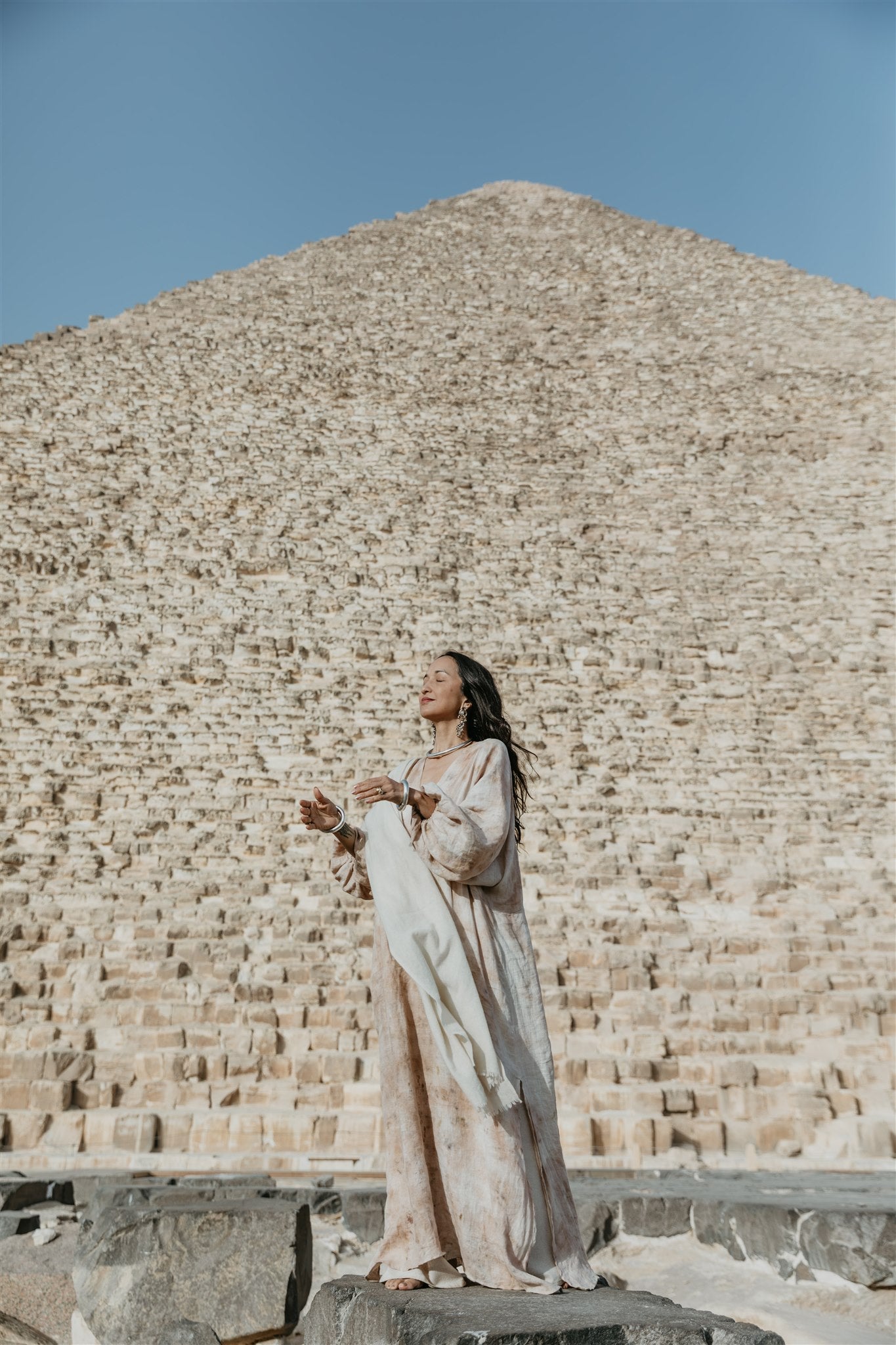 Woman Wearing Nomad linen kaftan in a  flowing botanical dyed linen dress standing in front of a pyramid in Egypt.