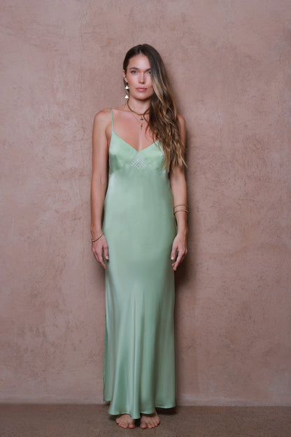 Woman wearing a green slip dress against a beige wall