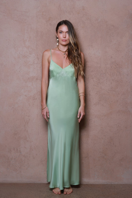 Woman wearing a green slip dress against a beige wall