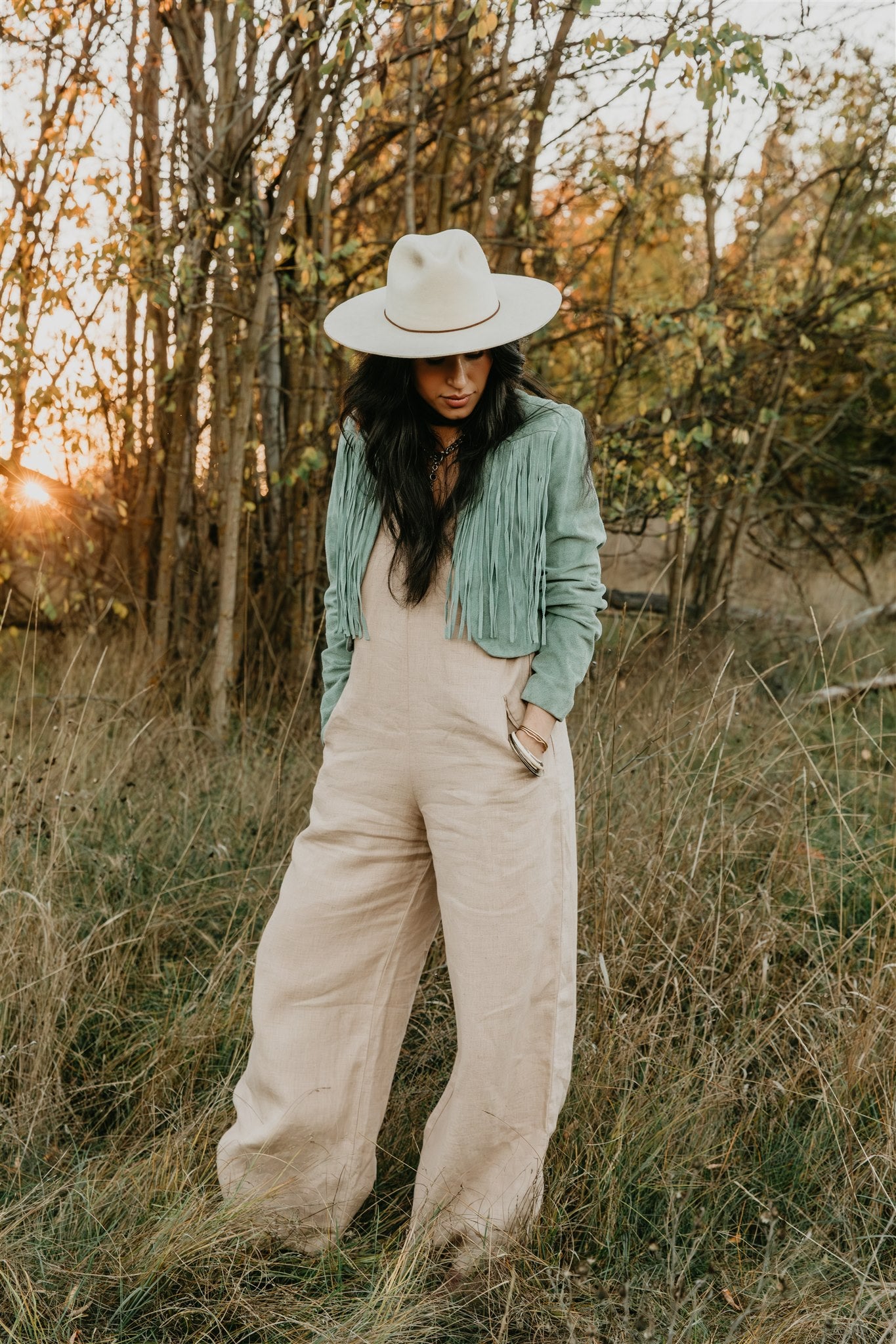 Woman in a hat and boho linen jumpsuit flowy silhouette in sunlight