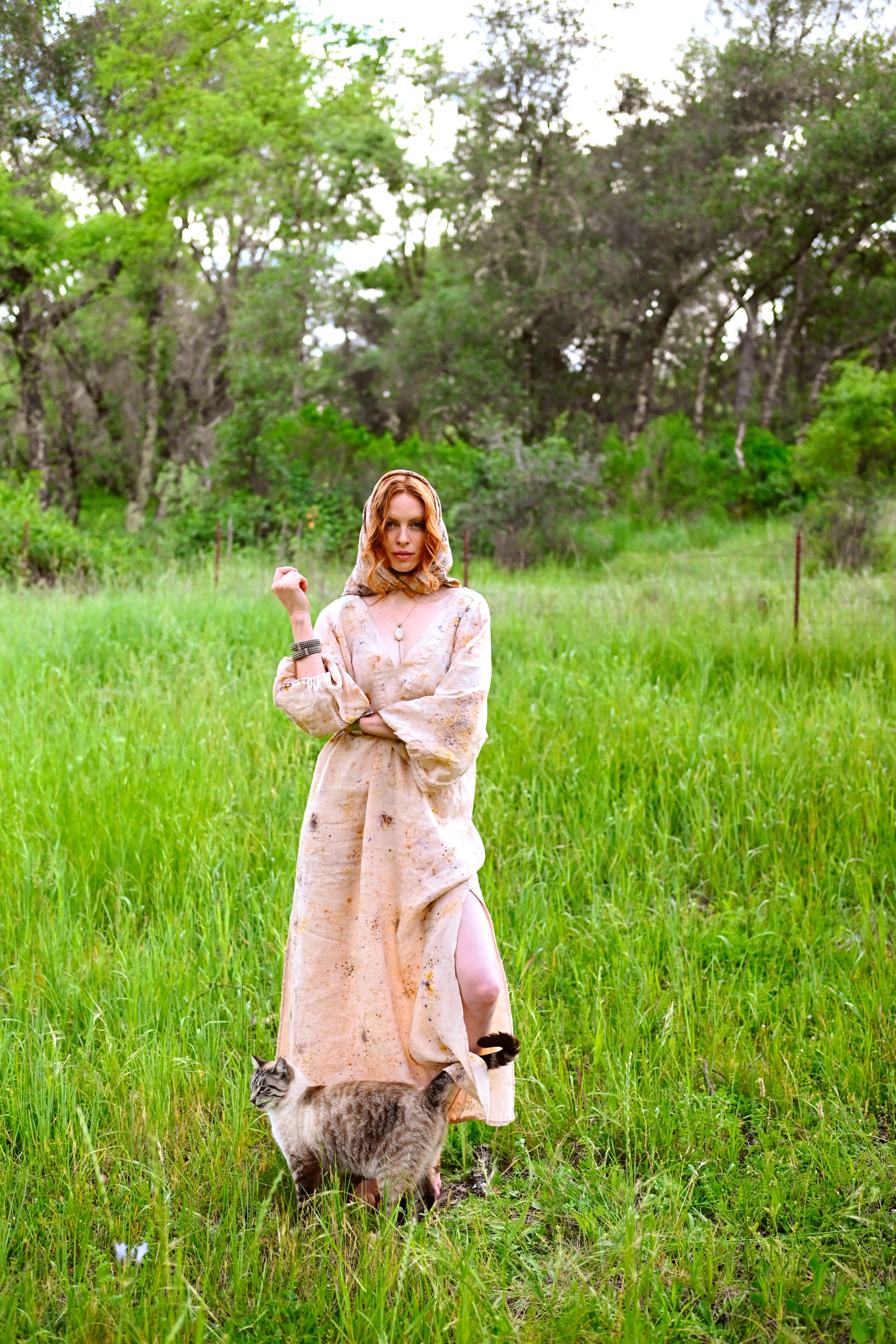Side slit detail on The Flora Dress in botanical-dyed linen, model walking through tall grass
