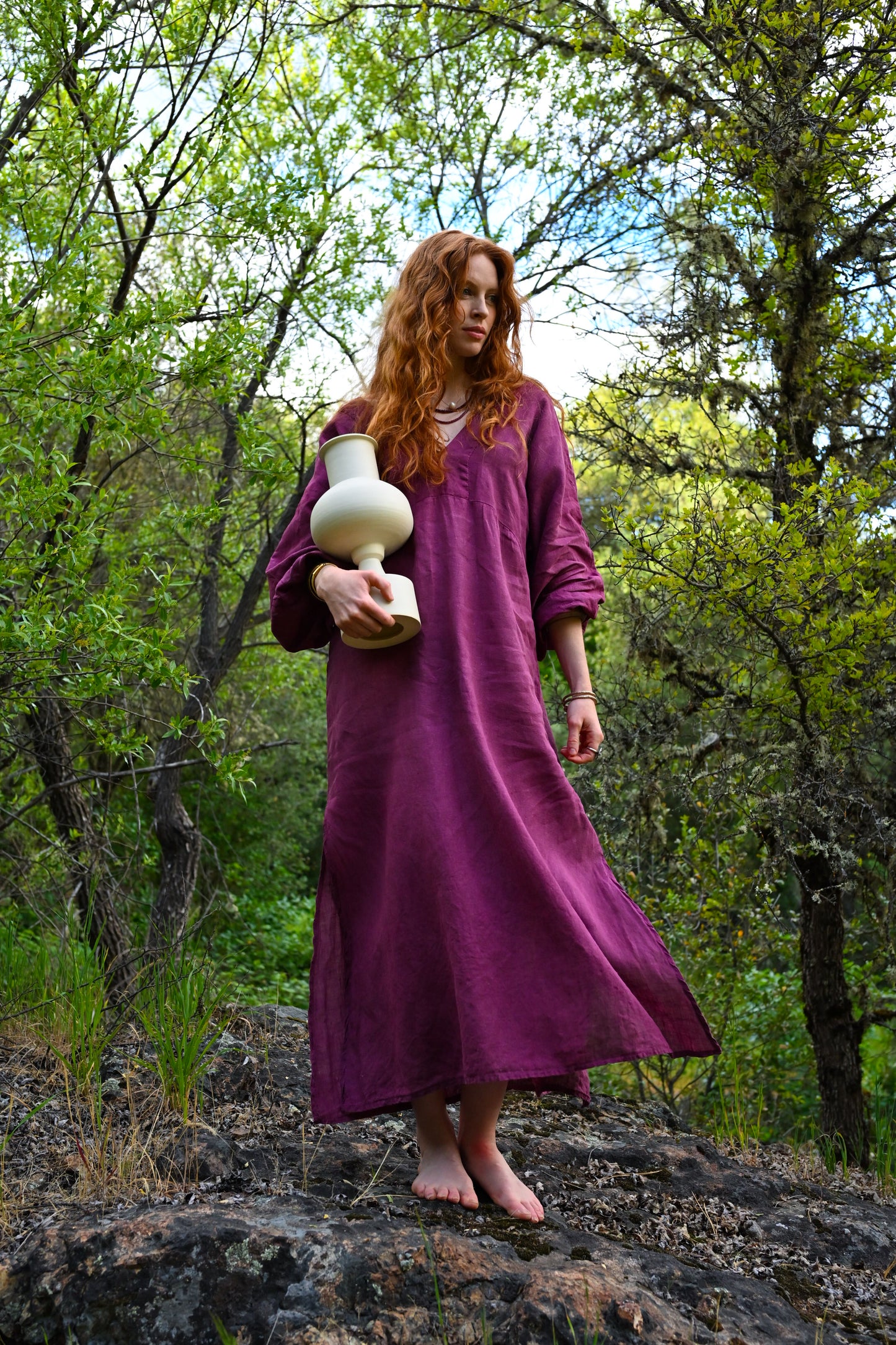 Side view of The Terra Dress in motion, plant-dyed linen flowing naturally, ankle-length with side slit visible