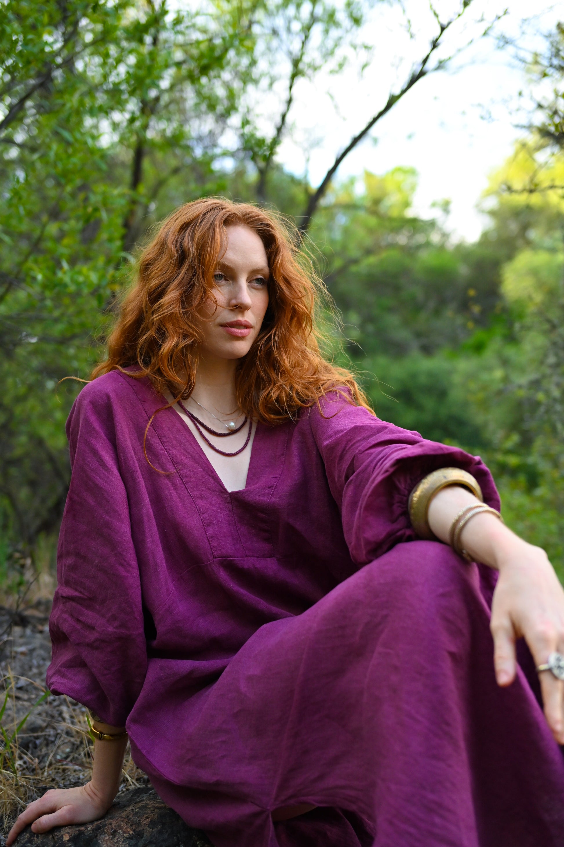 Woman in a purple dress sitting in a forest