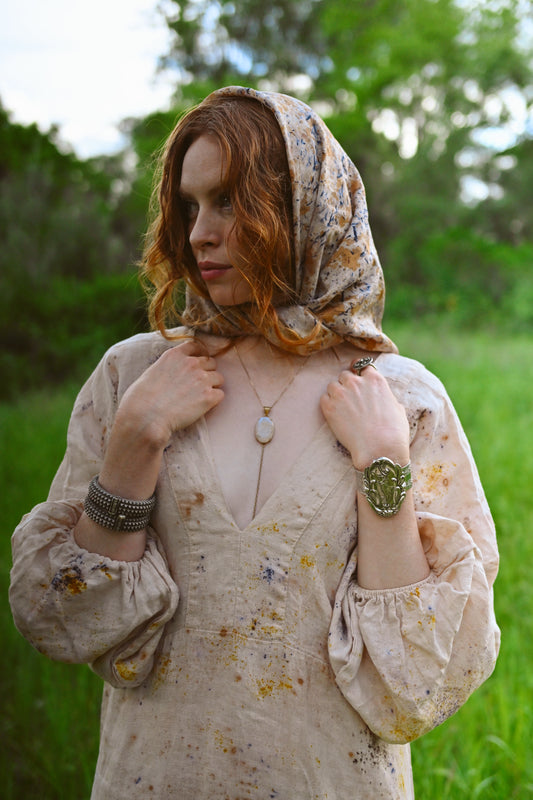 Deep V-neckline detail on The Flora Dress with botanical eco-print in golden amber and violet on natural cream linen by Payet Maison