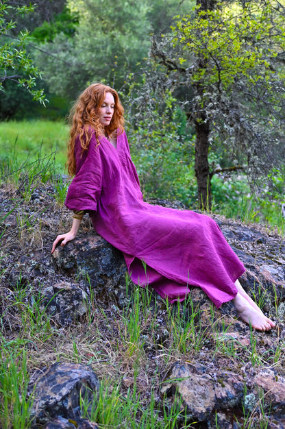 Ankle-length hem with side slit detail on The Terra Dress, plant-dyed linen in deep plum, bare feet on forest floor
