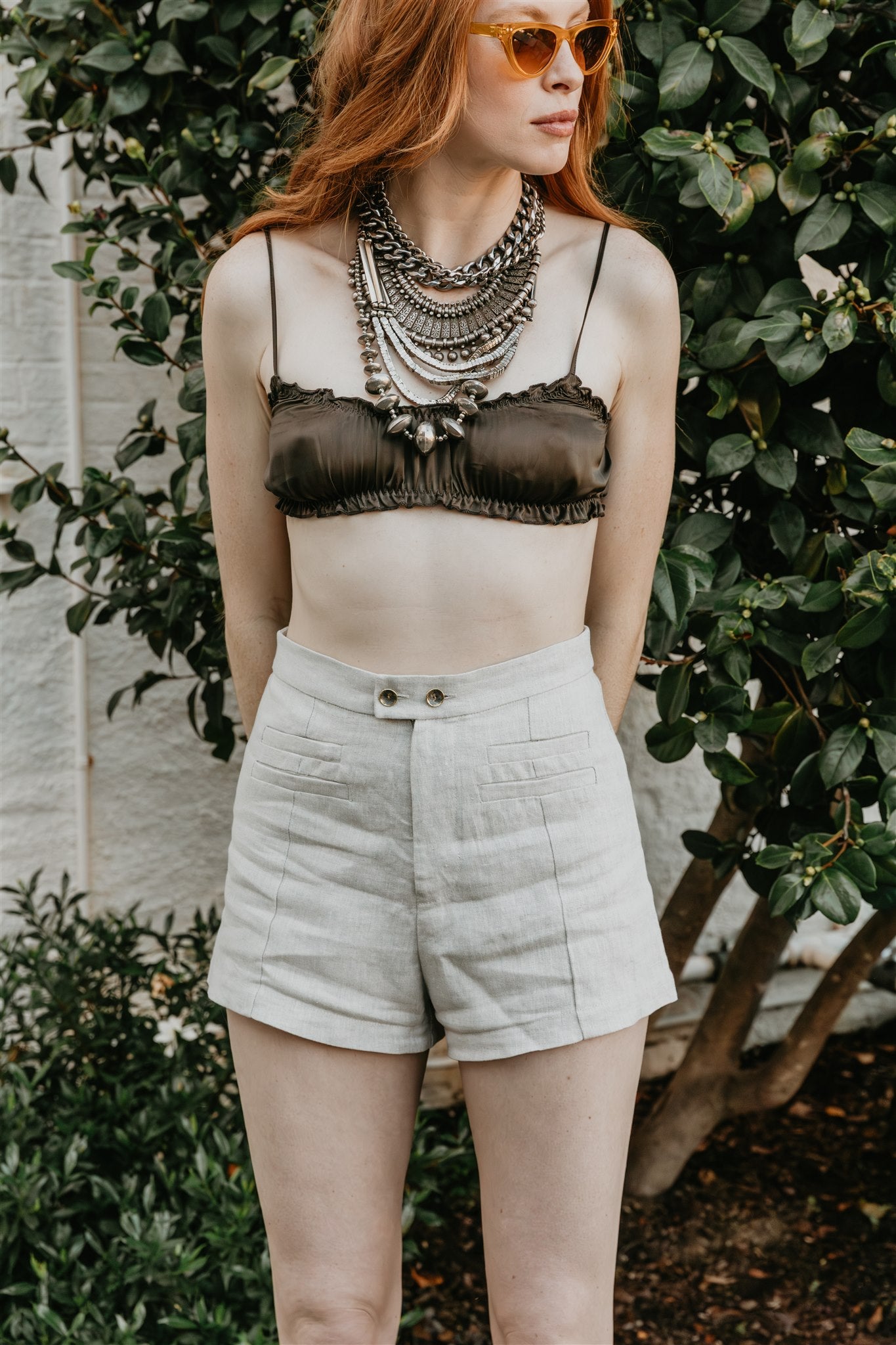 women wearing linen shorts with front pleats close up and licorice bralette silk
